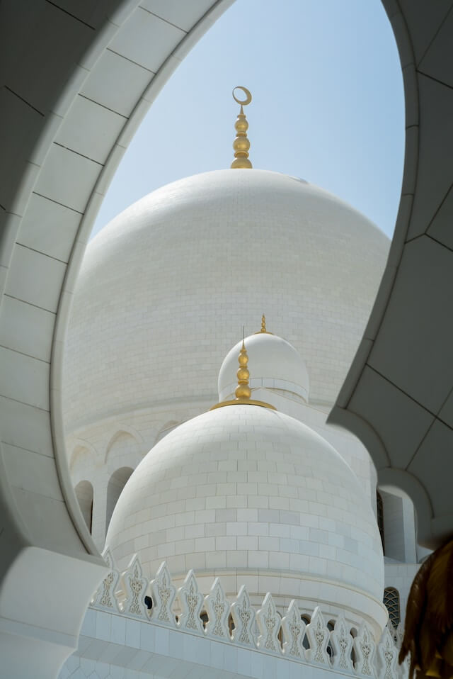 grand white mosque with blue sky in the background