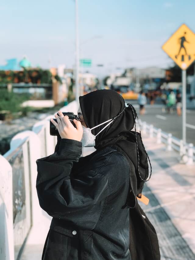 woman in hijab taking photo with camera